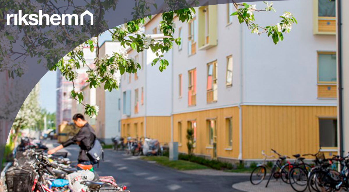 Lägenhetshus med träd, cyklar och en människa